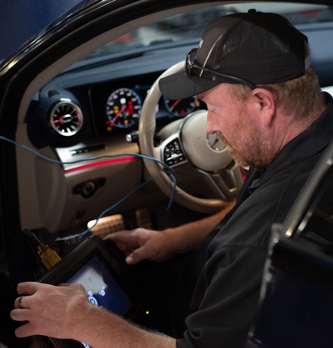 Technician using a diagnostic tablet inside a Mercedes-Benz