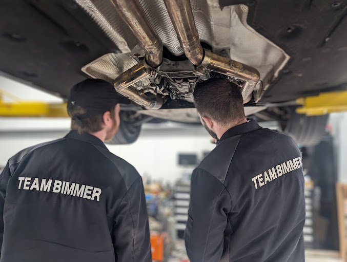 Two technicians inspecting the underside of a raised vehicle.